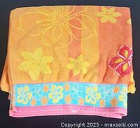 Folded view of vintage cotton bath towel showing orange color with yellow flowers and blue floral border.