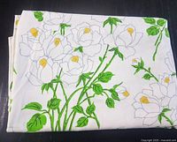 Folded flat sheet showing repeated floral pattern with grey rose outlines, green leaves, and yellow accents on white background.