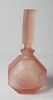 Front view of vintage frosted pink Balos perfume bottle with stopper showing geometric faceted bottle body and rectangular stopper.