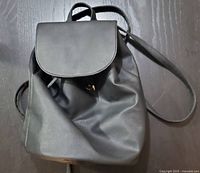 Full front view of black vegan leather knapsack backpack showing flap and straps