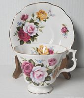 Photo of vintage Royal Albert footed teacup and matching saucer, showing detailed multi-colored floral designs and gold trim accents.