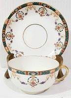 Front view of teacup with matching saucer displayed behind, showing decorative pattern and shape.