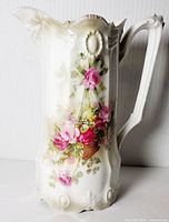 Large white porcelain water pitcher with sculpted floral oval details, hand painted roses in basket