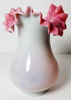 Front view of vintage Bohemian art glass vase showing smooth white to pink gradient body and decorative ruffled top edge.