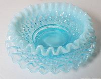 Close-up side view of blue opalescent hobnail glass candy dish showing ruffled edge and hobnail texture