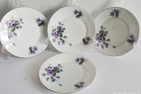 Overall view of all four vintage side plates with violet flower patterns and gold rims.