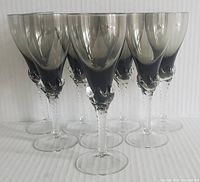Six Mid Century Murano aperitif glasses with smokey glass bowls and claw-shaped stems shown from front and side angles on a white ribbed surface.