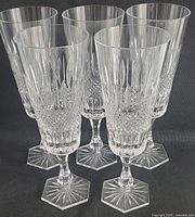 Set of five clear crystal goblets with detailed cut patterns, hexagonal starburst bases, standing grouped together.