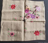 Front view of vintage linen pillow cover with colorful hand embroidery of flowers in purple, pink, red and orange on beige linen fabric.