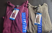 Two folded knit long sleeve tops, burgundy and olive green, both with size large tags and original packaging.