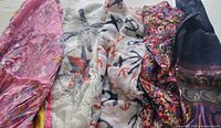 Five assorted vintage scarves laid out to show different colors and patterns including pink floral, nautical, and dark blue with gold accents