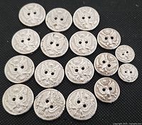 Top-down view of all 17 vintage metal buttons with a crest design, showing varying sizes and overall condition.