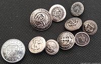 10 vintage metal buttons on dark surface, showing various designs including 'Toronto Metropolitan' and heraldic crests