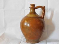 Front view of the large bulbous antique jug with handle showing glaze and texture details.