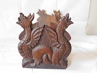 Close up of one end of the wooden book slide showing the detailed hand carved dragon motif with scales, wings, and open mouth.