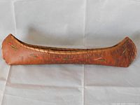 Side profile photo of the antique birch bark canoe displaying porcupine quill decorations on the side.