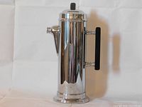 Full frontal view of the Art Deco cocktail shaker showing polished stainless chrome body, square black knob on lid and square handle.