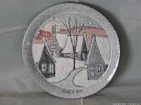 Front view of the hand painted plate showing Quebec village winter scene, artist signature visible