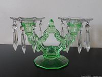 Front view of vintage green glass double candle holder with crystal drops and wax drip guards