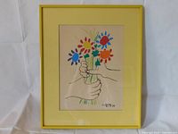 Front view of framed Picasso print with yellow frame and mat, showing colorful flowers and hands.