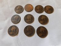 Top-down view of all 10 large Victorian pennies arranged in a group on white cloth.