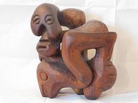 Front and side view of abstract hand carved wood sculpture with facial and limb details.