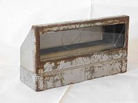 Side view of the rectangular metal WWII tank periscope showing worn and rusted metal casing with glass window.