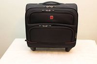 Front view of black Swiss Gear carry-on suitcase showing multiple zippered compartments and Swiss cross logo on front