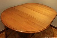 Photo of the wooden oval kitchen table with a natural wood finish, showing the tabletop without extension leafs.