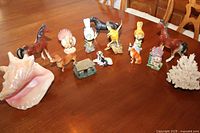 Full arrangement of all figurines on wooden table showing variety including horses, animals, house and shell