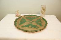 Wide view of all three items on a table: the scalloped green and gold Florentine tray, small floral jug, and tall porcelain vase.