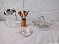 Photo showing all items together: lemon juicer, syrup dispenser, salt cellar, fondue forks in holder