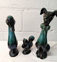 Front view of three Blue Mountain Pottery animal statues - duck, squirrel, and sitting dog.