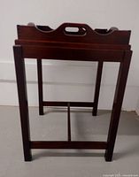 Side view of wooden butler table with legs and cross brace structure visible.