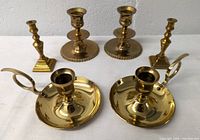 Front view of all three pairs of brass candle holders arranged in two rows on white surface.