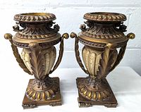 Pair of bronze tone urns with acanthus leaf accents, showing full front view.