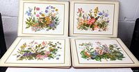 Four Pimpernel place mats upright showing different floral designs with gold border