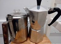 Bialetti aluminum Moka pot and stainless steel coffee percolator side by side on wood surface