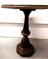 Side view of the pedestal base showing its octagonal shape and dark brown finish with gold accent.
