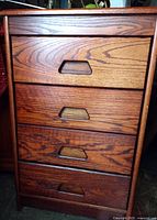 Front view of wood cabinet showing four drawers with finger cutout handles.