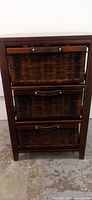 Front view of wooden side table with three rattan drawers with leather handles