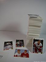 Stack of hockey cards with four sample cards displayed in front showing players in various team uniforms, mostly goalies.