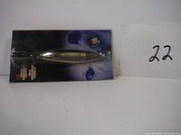 Blue Fox More-Silda fishing spoon lure in original blue-black packaging showing front side of lure and treble hook.