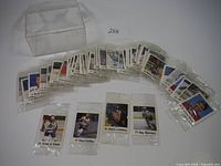 Wide view showing multiple 1988 chip bag hockey cards sealed in individual transparent bags laid out in row with clear plastic container behind them.