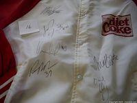 Close-up photo of front upper jacket with multiple hockey player autographs in black ink, Diet Coke logo visible.