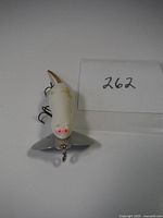 Front view of the white mouse shaped fishing lure with metal lip and treble hooks, catalog number 262 displayed.
