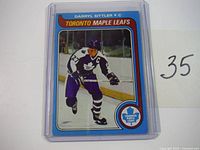 Photo of 1979-80 Darryl Sittler hockey card in protective plastic case, showing front design with player skating and team logo