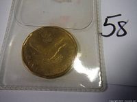 2006 Canadian Olympic Loonie coin in protective plastic sleeve showing the engraved loon image and year 2006.