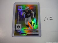 2022 Donruss Gold Holo Press Proof football card showing Maxx Crosby in Raiders uniform, numbered 112 handwritten on card edge.