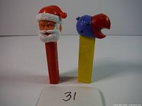Front view of two PEZ dispensers: Santa Claus and parrot, with a card labeled '31' in front